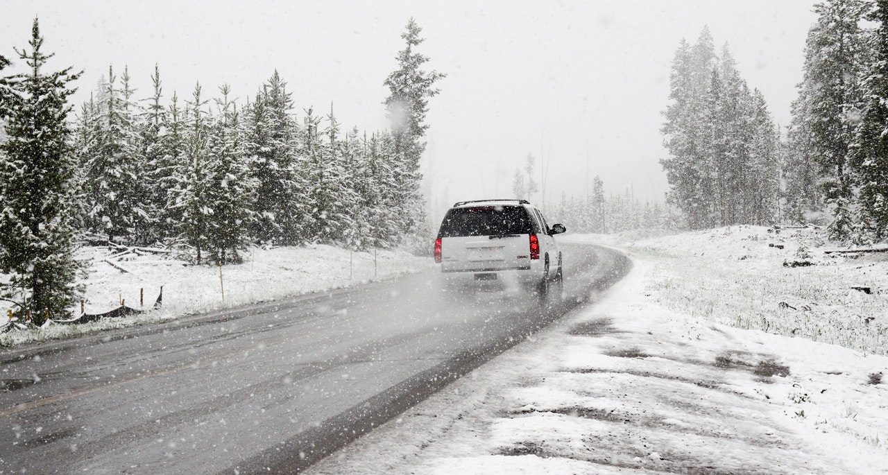 7 holiday driving tips White SUV on road near snow-covered trees