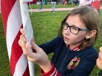 Young girl reads a note attached to American flag