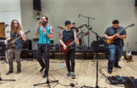 Three guitarists play with the lead singer
