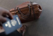 COVID-19 restricts students’ travel options Traveler with passport and brown leather duffel bag in focus