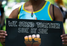 LGBTQ pride: Going beyond the rainbow flag Sign reads "We stand together side by side, full of color and bleeding pride!"
