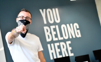 Gender and Sexuality Student Resource Center strives to cultivate community Peter pointing at camera next to "You Belong Here" on back wall