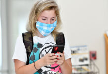 Navigating MySLCC Student browses phone while wearing light blue mask