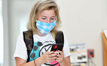 Navigating MySLCC Student browses phone while wearing light blue mask