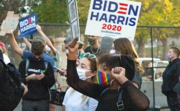 Protesters eye bigger issues than Pence and Harris Black protester wears rainbow-colored mask