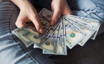 How students are utilizing stimulus checks Person holding several U.S. 100-dollar bills