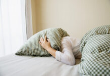 Sleep challenges worsened by pandemic Woman covers her head with a pillow while in bed