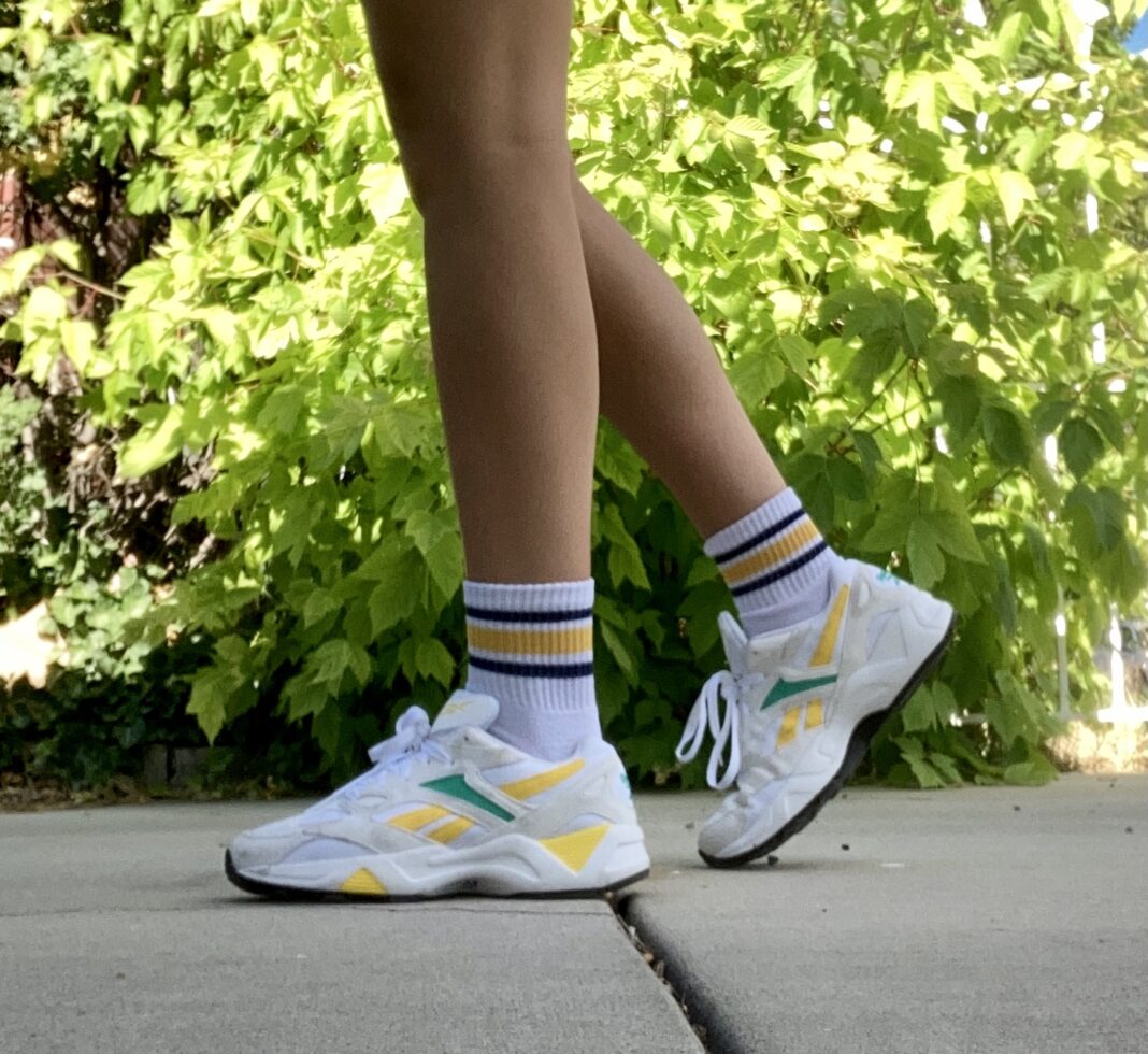 Person wearing white socks and shoes with yellow and blue trim