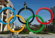 SLCC alum heads to 2020 Tokyo Olympics Eddy Alvarez sitting on top of Olympic Rings