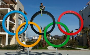 SLCC alum heads to 2020 Tokyo Olympics Eddy Alvarez sitting on top of Olympic Rings