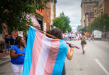 The impact of deadnames Person walking with transgender pride flag during Baltimore Pride event