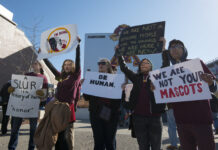 Decades of activism helping to eliminate Native American mascots Multiple protesters hold signs denouncing Washington Redskins