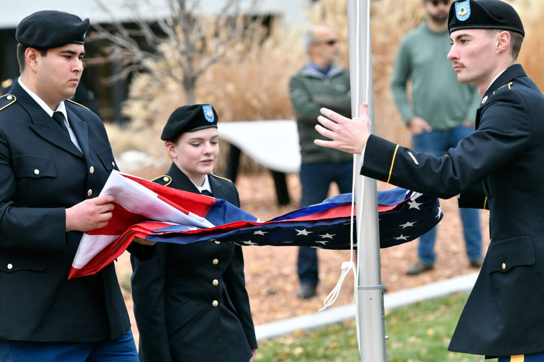 Three cadets unfurl American Flag