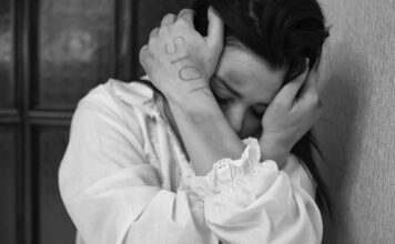 Dirty words: Domestic violence; lifting the stigma Stop written on battered woman's hand as she holds bruised arms over her face