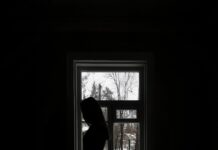 SLCC counselor offers insight into seasonal affective disorder Pensive female standing near window in dark room