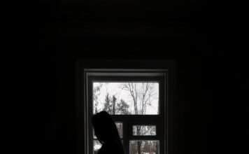SLCC counselor offers insight into seasonal affective disorder Pensive female standing near window in dark room