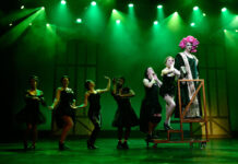 Entertainment on a budget at the historic Grand Theatre Seven theater actors wear black costumes on a stage under green lights