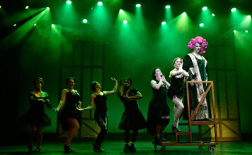 Entertainment on a budget at the historic Grand Theatre Seven theater actors wear black costumes on a stage under green lights