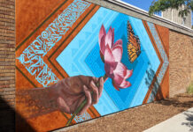 Alumni come full circle with mural for SLCC’s Peace and Justice Garden Brick wall decorated with multicolored mural of a hand, lotus flower and butterfly