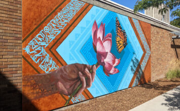Alumni come full circle with mural for SLCC’s Peace and Justice Garden Brick wall decorated with multicolored mural of a hand, lotus flower and butterfly