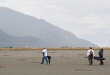 Lake questions: What are the effects of a dried Great Salt Lake on locals and wildlife? Three people walk along the lake bed looking for garbage