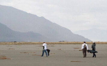 Lake questions: What are the effects of a dried Great Salt Lake on locals and wildlife? Three people walk along the lake bed looking for garbage