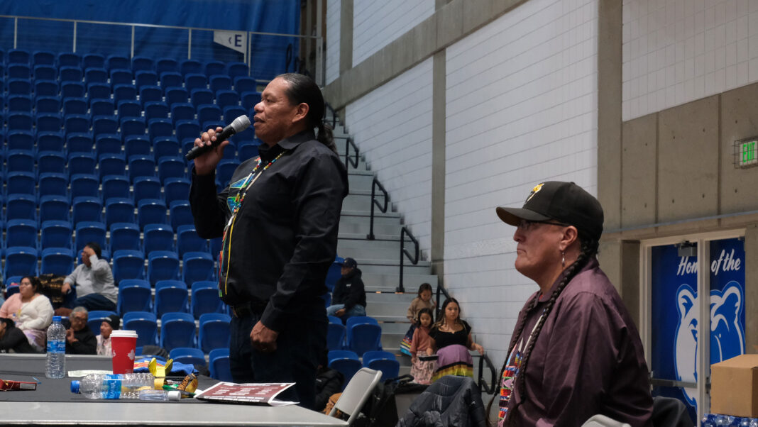 Bart Powaukee, left, speaks into microphone