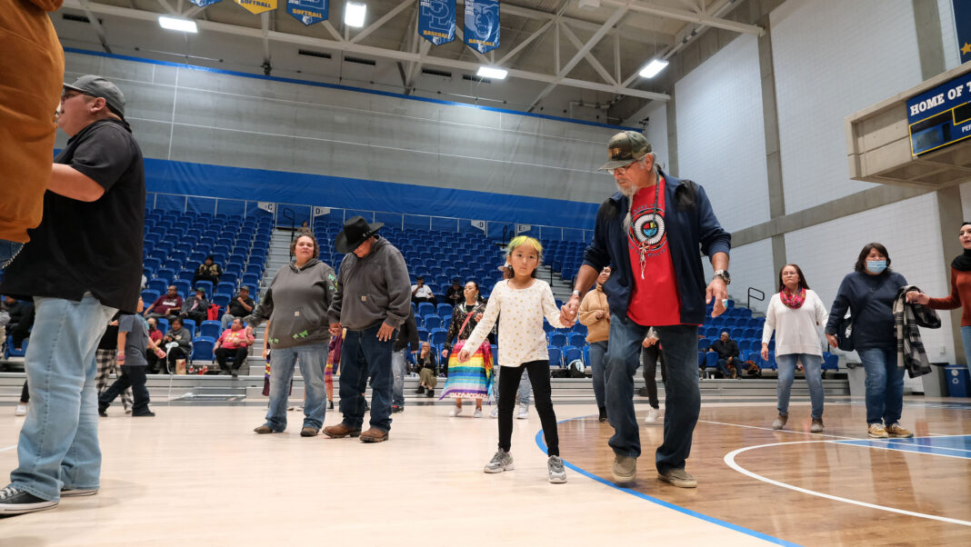 People hold hands and dance inside a gym