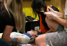 EMT students participate in mass casualty event to prepare for real-life emergencies EMT students gather around a patient actor wearing a neck brace during a training exercise