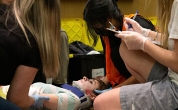 EMT students participate in mass casualty event to prepare for real-life emergencies EMT students gather around a patient actor wearing a neck brace during a training exercise