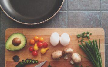 How SLCC students can boost their nutrition on a budget Knife resting on a kitchen cutting board with avocado, tomatoes, eggs, mushrooms, spring onions, and leaves
