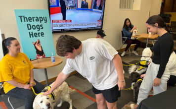 3-day event helps students relax during finals, reminds them of available help Student in white t-shirt pets a golden retriever
