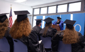 23 students graduate from SLCC’s Prison Education Program Two rows of graduates sitting and listening to David Bokovoy speak at podium