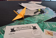 Crafting cranes event generates awareness for mental health resources An orange paper crane and mental health flyers sit on a table