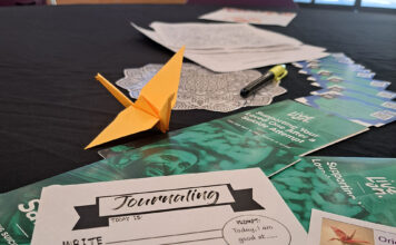 Crafting cranes event generates awareness for mental health resources An orange paper crane and mental health flyers sit on a table