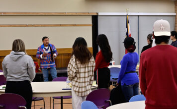 Indigenous storyteller, filmmaker tells Ute tales for SLCC event Larry Cesspooch, facing audience, leads a prayer on stage
