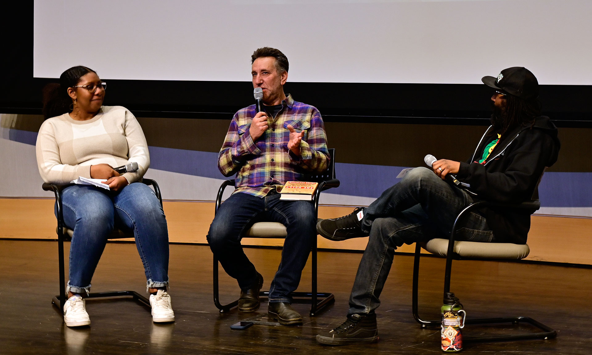 Three panelists discussing a film while seated on stage