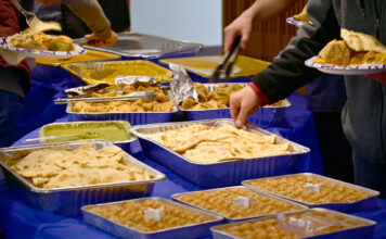 People of all backgrounds come together for SLCC’s interfaith iftar People using serving utensils to select food from trays