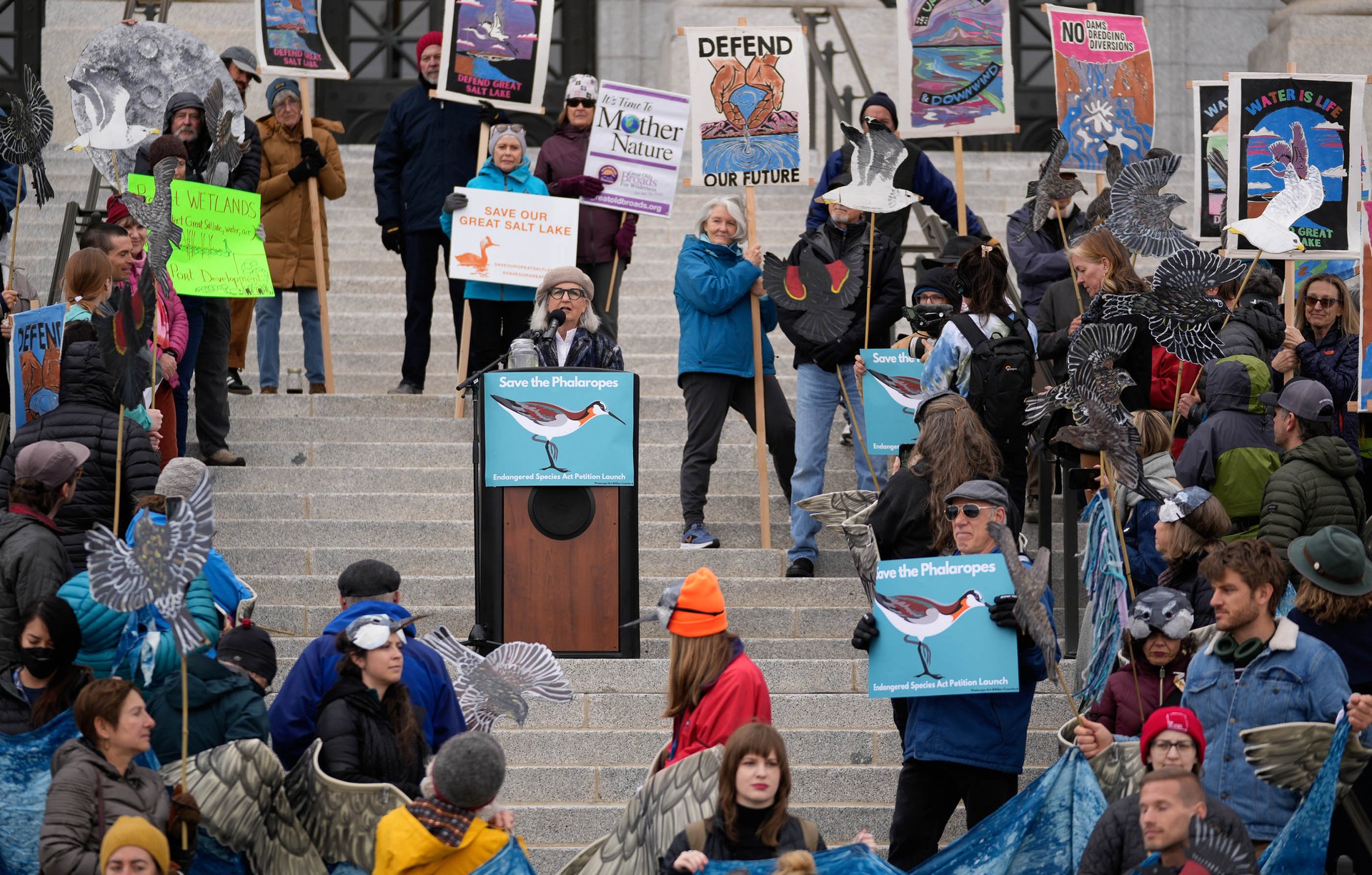 Terry Tempest Williams standing at podium surrounded by environmental advocates