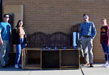 Four students organize furniture drive for victims of domestic violence Four students standing next to donated furniture