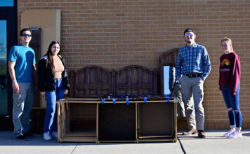 Four students organize furniture drive for victims of domestic violence Four students standing next to donated furniture