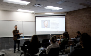 Veteran Boston Globe editor gives talk at Salt Lake Community College Seated audience listening to guest lecturer James Dao, whose picture and information is displayed on a projection screen