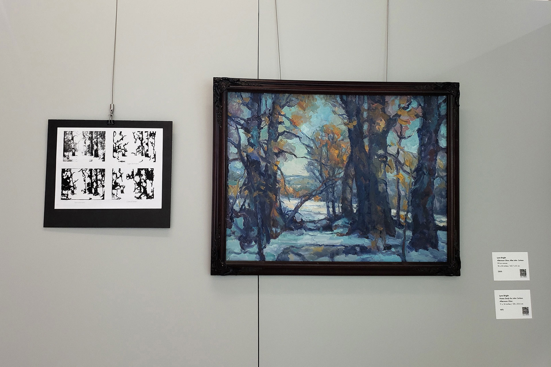 A small framed picture of Notan studies and the final landscape painting displayed on a wall in a gallery
