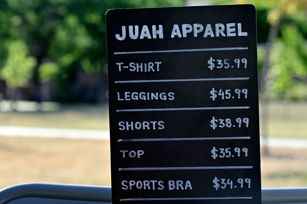 Black sign with white text detailing clothing items for sale by Juah Apparel