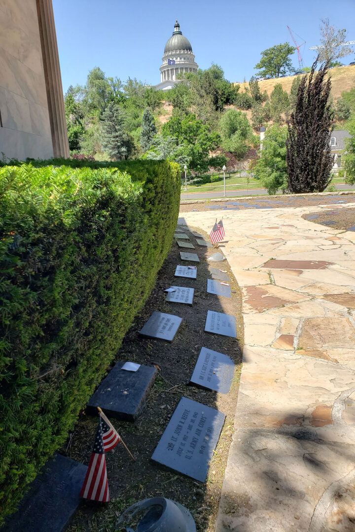 Markers line a pathway next to chapel, Utah State Capitol in the background
