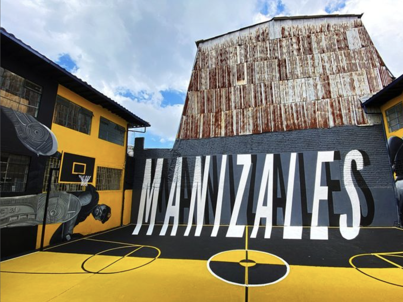Basketball court painted in dark blue and yellow colors with "Manizales" written in white text