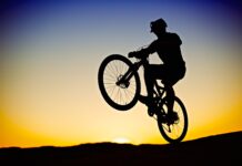 Several athletes with Utah ties to compete at the Paris Olympics Silhouette of man pulling a classic wheelie on a mountain bike