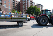 Families celebrate new experiences and classic traditions on Pioneer Day Tractor pulling trailer filled with people on a parade route