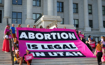 Utah Supreme Court decision to uphold block on abortion trigger law elicits many viewpoints Dozens of people sit on capitol building steps with a sign that reads "abortion is legal in Utah"