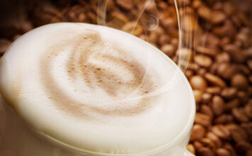 Fall’s favorite drink: the pumpkin spice latte A cup of coffee with coffee beans in background